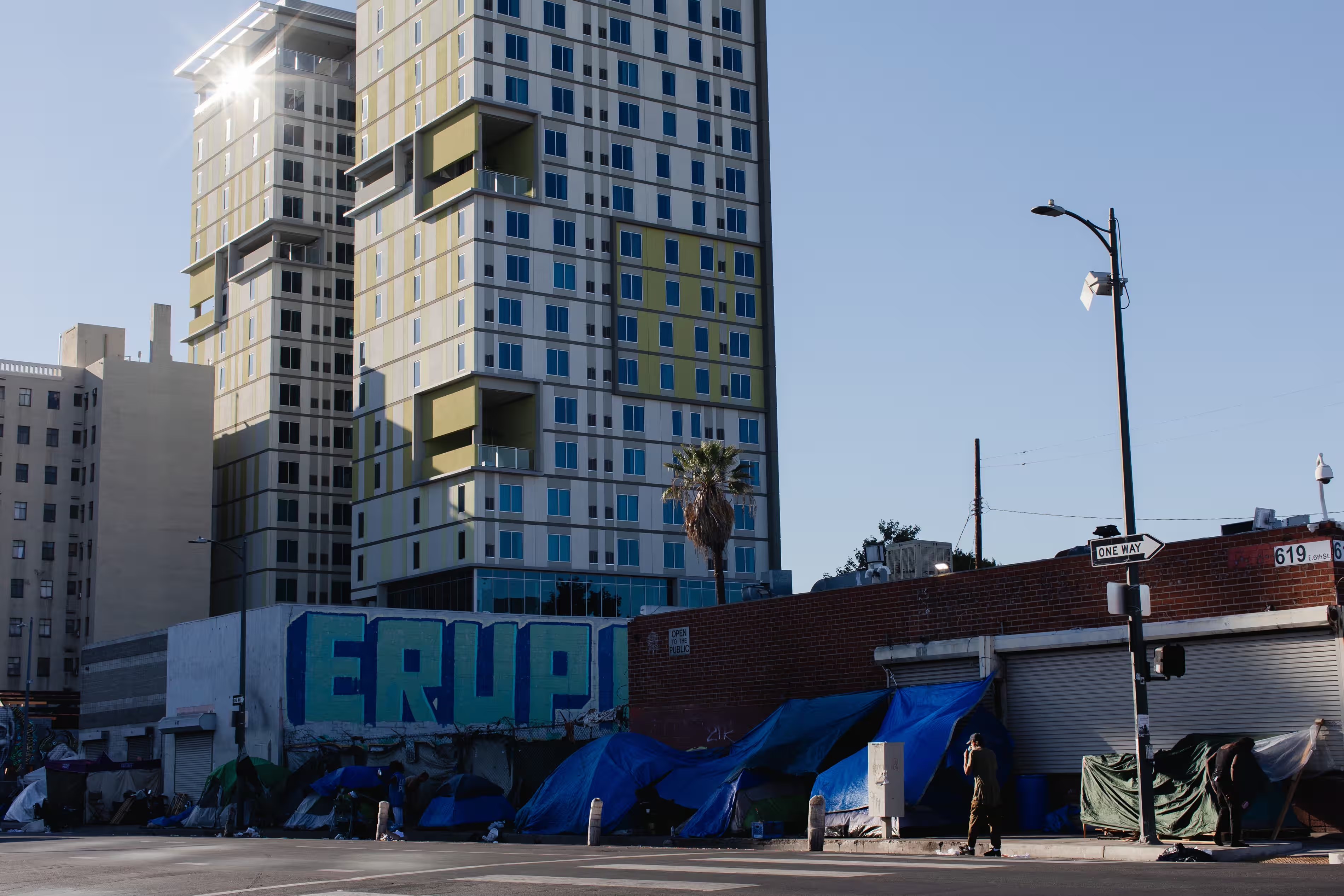 Homeless encampments sit beneath a new permanent supportive housing development in Los Angeles. Photograph: Alex Welsh/The Guardian