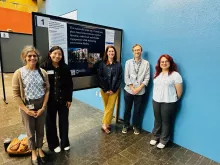 The Vijayaraghvan team standing near a poster presentation.