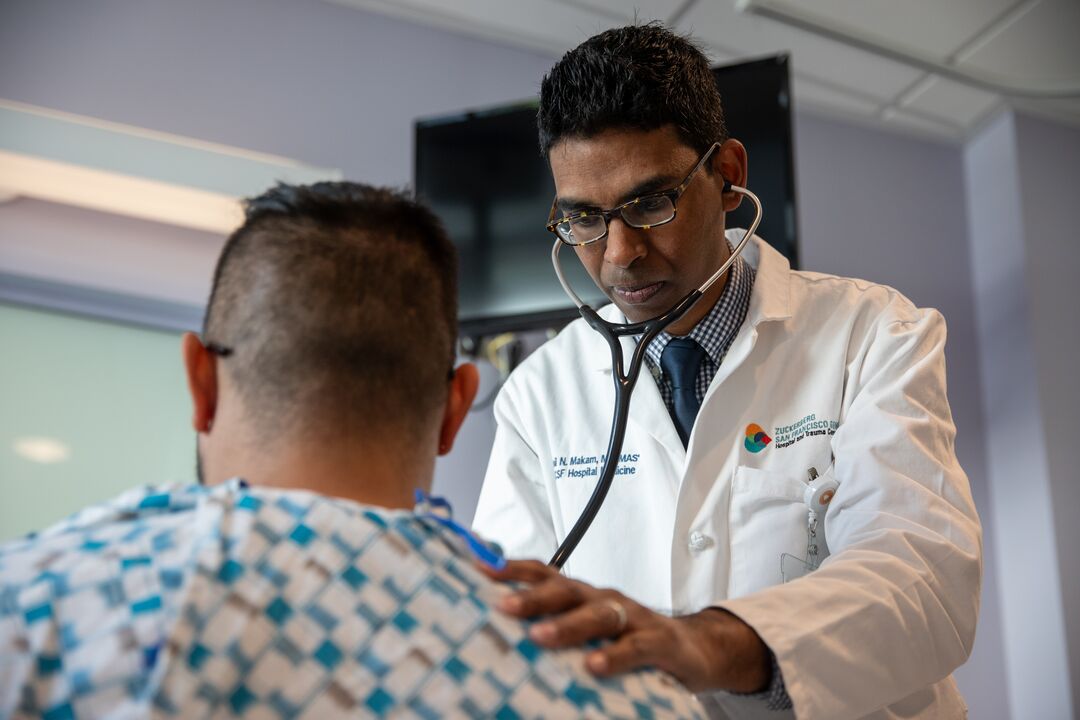 Dr. Anil Makam works with a patient in an ICU room at Zuckerberg San Francisco General Hospital in San Francisco, CA on Monday, April 8, 2024. Dr. Makam’s research looks at the long-term effects of severe Covid illness among the sickest of survivors early in the pandemic.